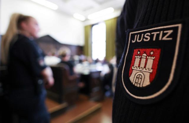 A logo on the uniform of a justice official is pictured as the defendants sit in the courtroom of the criminal justice building at the start of another day of hearings in the trial against the far-right terrorist group Last Wave of Defense, on August 5, 2026 in Hamburg. A German court gave prison sentences of up to five years on August 5, 2026 to seven alleged members or supporters of a German far-right militant group called the "Last Wave of Defence".
The men, all in their teens or early 20s, were convicted of crimes including membership in a terrorist organisation, attempted murder and arson for plotting attacks on refugees and left-wing activists. (Photo by Christian Charisius / POOL / AFP)
