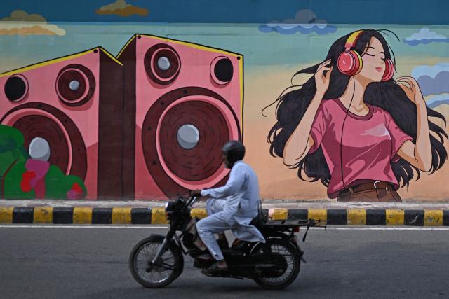 A motorist rides past a mural along a street in New Delhi on August 5, 2026. (Photo by Sajjad HUSSAIN / AFP)