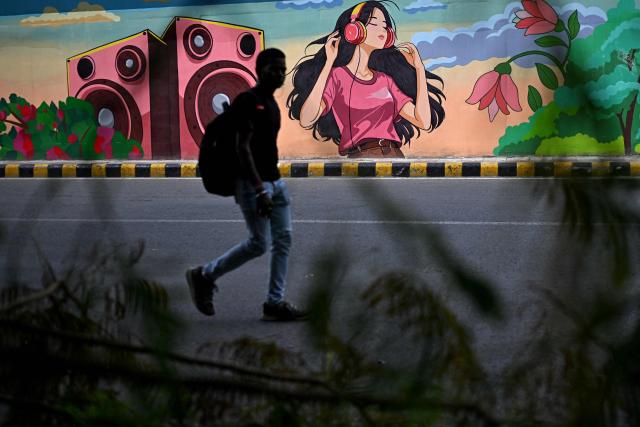 A pedestrian walks past a mural along a street in New Delhi on August 5, 2026. (Photo by Sajjad HUSSAIN / AFP)