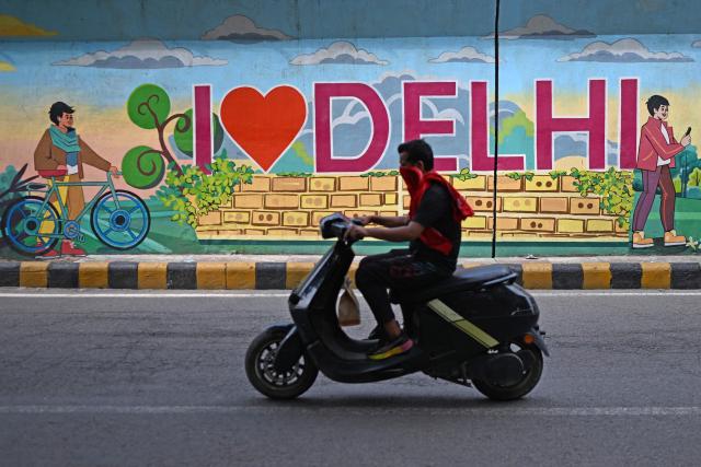 A motorist rides past a mural along a street in New Delhi on August 5, 2026. (Photo by Sajjad HUSSAIN / AFP)