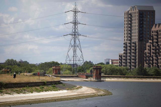 A pedestrian (L) walks along the path around Lockwood Reservoir near Walthamstow in north London on August 5, 2026, as the UK Met Office weather agency said on August 3 that England and Wales both experienced the "driest July on record". London and its suburbs are one of 19 English regions to have had no more than one millimetre of rainfall in July, with water companies in parts of England and Wales imposing bans on using hose pipes for household tasks and watering plants. (Photo by Henry Nicholls / AFP)