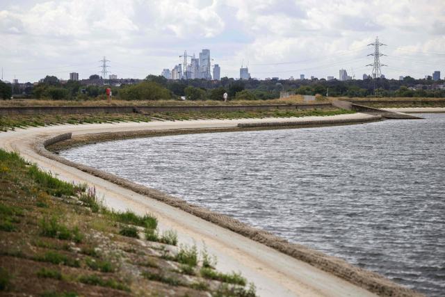 A pedestrian (top C) walks along the path around Lockwood Reservoir near Walthamstow in north London on August 5, 2026, as the UK Met Office weather agency said on August 3 that England and Wales both experienced the "driest July on record". London and its suburbs are one of 19 English regions to have had no more than one millimetre of rainfall in July, with water companies in parts of England and Wales imposing bans on using hose pipes for household tasks and watering plants. (Photo by Henry Nicholls / AFP)