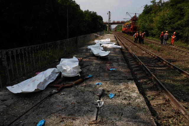 EDITORS NOTE: Graphic content / Railway workers gather on railway tracks next to bodies in plastic bags of people killed during Russian ballistic missile and drone strikes at a railway station in the Kyiv region on August 5, 2026, amid the Russian invasion of Ukraine. Russian missile and drone strikes killed at least 17 people and wounded dozens more in Kyiv and the surrounding region overnight, authorities said on August 5, 2026. (Photo by Mykola TYMCHENKO / AFP)