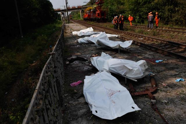 EDITORS NOTE: Graphic content / Railway workers gather on railway tracks next to bodies in plastic bags of people killed during Russian ballistic missile and drone strikes at a railway station in the Kyiv region on August 5, 2026, amid the Russian invasion of Ukraine. Russian missile and drone strikes killed at least 17 people and wounded dozens more in Kyiv and the surrounding region overnight, authorities said on August 5, 2026. (Photo by Mykola Tymchenko / AFP)