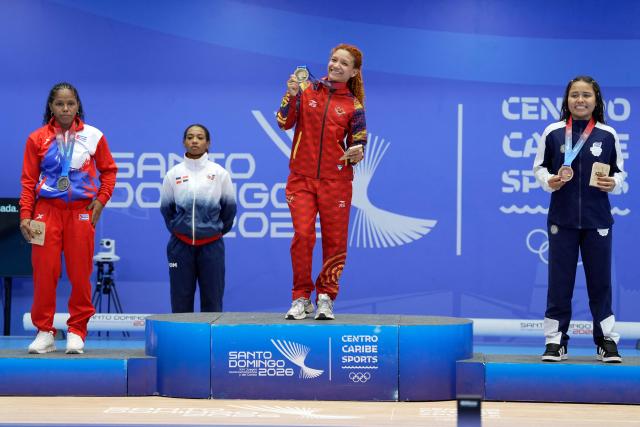 (L to R) Cuba's Ludia Montero, Venezuela's Patricia Mercado and El Salvador's July Mendoza stand on the podium after winning the gold, silver and bronze medals, respectively, in the women's 48Kg weightlifting event during the XXV Central American and Caribbean Games in Santo Domingo on August 5, 2026. (Photo by Francesco SPOTORNO / AFP)