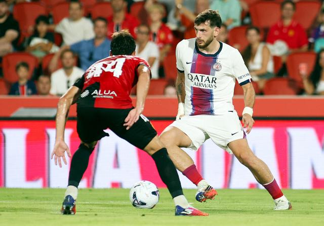 Paris Saint-Germain's Georgian forward #07 Khvicha Kvaratskhelia (R) is challenged by Real Mallorca's Spanish defender #44 Miguel Calatayud during the Ciutat de Palma trophy friendly football match between Mallorca RCD and Paris Saint-Germain FC at Mallorca Son Moix Stadium in Palma de Mallorca on August 8, 2026. (Photo by JAIME REINA / AFP)