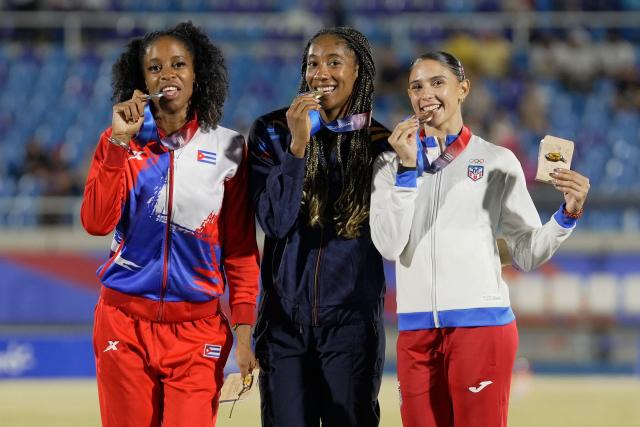 Colombia's Maria Murillo (C), Cuba's Greisys Roble (L) and Puerto Rico's Paola Vazquez pose on the podium after winning the gold, silver and bronze medals, respectively, in the women's 100m hurdles final during the XXV Central American and Caribbean Games at the Felix Sanchez Olympic Stadium in Santo Domingo on August 5, 2026. (Photo by Francesco SPOTORNO / AFP)