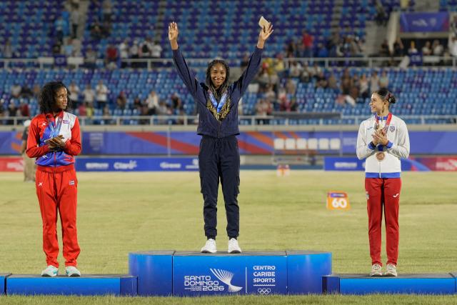Colombia's Maria Murillo (C), Cuba's Greisys Roble (L) and Puerto Rico's Paola Vazquez stand on the podium after winning the gold, silver and bronze medals, respectively, in the women's 100m hurdles final during the XXV Central American and Caribbean Games at the Felix Sanchez Olympic Stadium in Santo Domingo on August 5, 2026. (Photo by Francesco SPOTORNO / AFP)