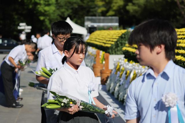 Representatives of Hiroshima's children offer flowers at the Peace Memorial Ceremony, on the 81st anniversary of the dropping of the atomic bomb, at the Peace Memorial Park in Hiroshima on August 6, 2026. (Photo by JIJI Press / AFP) / Japan OUT