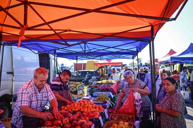 Customers buy fruits vegetables from local farmers selling produce on stalls under tents at the open-air market in the city of Calarasi, Romania, on July 26, 2026. As the eastern European country has struggled for months with the highest inflation in the European Union, almost 11 percent in May, several buyers complained of rising prices which forced them to make difficult decisions about what to cut. (Photo by Daniel MIHAILESCU / AFP)