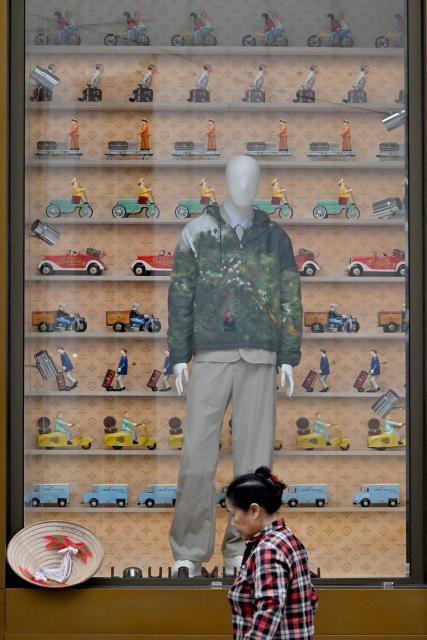 A woman stands in front of a fashion store in Hanoi on August 6, 2026. (Photo by Nhac NGUYEN / AFP)
