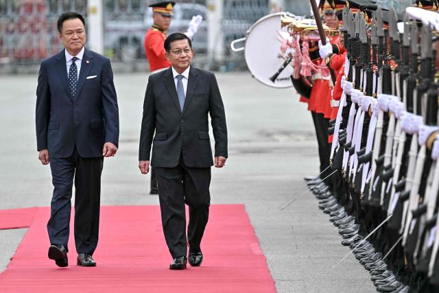 Myanmar's President Min Aung Hlaing (C) and Thailand's Prime Minister Anutin Charnvirakul (L) inspect a guard of honour at a welcoming ceremony during his visit at Government House in Bangkok on August 6, 2026. (Photo by Lillian SUWANRUMPHA / AFP)