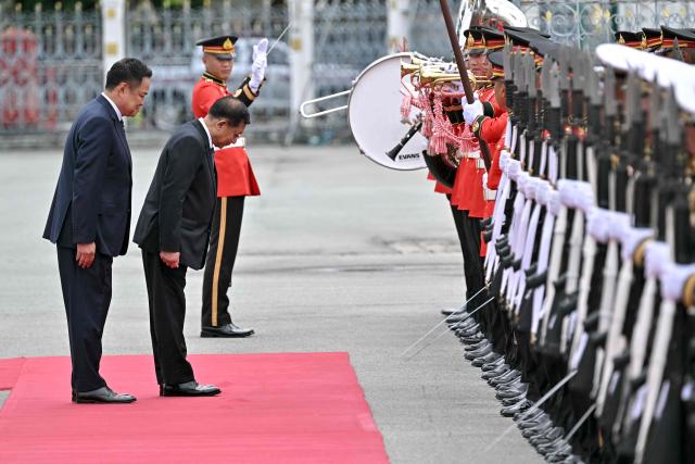 Myanmar's President Min Aung Hlaing (2nd L) and Thailand's Prime Minister Anutin Charnvirakul (L) inspect a guard of honour at a welcoming ceremony during his visit at Government House in Bangkok on August 6, 2026. (Photo by Lillian SUWANRUMPHA / AFP)