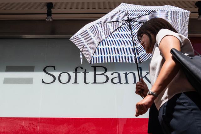 A commuter walks past a Softbank logo on the side of a building in Tokyo on August 6, 2026. (Photo by Andrew CABALLERO-REYNOLDS / AFP)