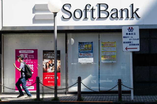 A man runs past a SoftBank office in Tokyo on August 6, 2026. (Photo by Andrew CABALLERO-REYNOLDS / AFP)