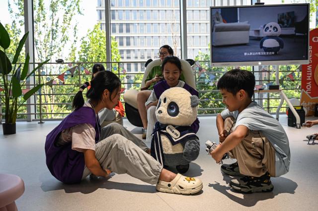 The photo taken on August 4, 2026 shows children playing with robot Pangda at the Hangzhou Robot school in Hangzhou, in eastern China's Zhejiang province. (Photo by Jade GAO / AFP)