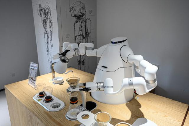 The photo taken on August 4, 2026 shows a robot manufactured by Zhejiang University Robot Research Institute making making coffee at the Hangzhou Robot school in Hangzhou, in eastern China's Zhejiang province. (Photo by Jade GAO / AFP)