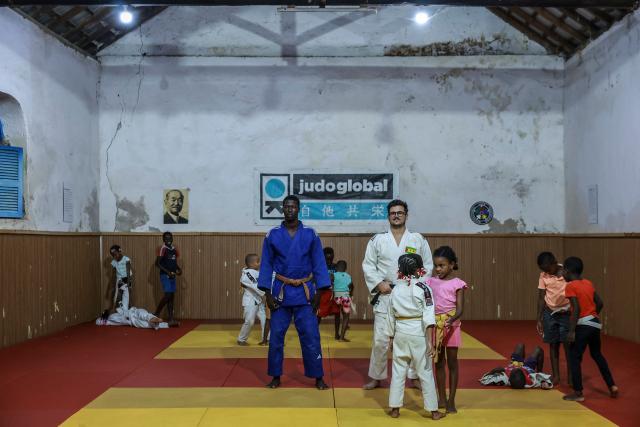 Judo instructor from Portugal Andre Mendes Rosa (R), 38, and Sao Tome and Principe's Nelson Pina (C-L) practitioner and instructor supervise young judokas in one of Judo Global dojos in Santo Antonio, in Principe Island in Sao Tome and Principe, on August 5, 2026. Andre Mendes Rosa, president and founder of Judo Global, set up the association to enable young people to discover the sport and develop through sport and education. The organisation now has six centres, three on the island of Sao Tome and three on the island of Principe. It is recognised by the International Judo Federation, and athletes from Judo Global centres take part in national, regional and even international competitions with a judoka from Sao Tome and Principe, for the first time, took part in the Olympic Games in Paris in 2024. (Photo by Daniel BELOUMOU OLOMO / AFP)