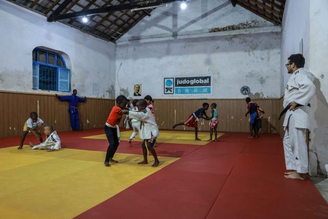 Judo instructor from Portugal Andre Mendes Rosa (R), 38, and Sao Tome and Principe's Nelson Pina practitioner and instructor supervise young judokas in one of Judo Global dojos in Santo Antonio, in Principe Island in Sao Tome and Principe, on August 5, 2026. Andre Mendes Rosa, president and founder of Judo Global, set up the association to enable young people to discover the sport and develop through sport and education. The organisation now has six centres, three on the island of Sao Tome and three on the island of Principe. It is recognised by the International Judo Federation, and athletes from Judo Global centres take part in national, regional and even international competitions with a judoka from Sao Tome and Principe, for the first time, took part in the Olympic Games in Paris in 2024. (Photo by Daniel BELOUMOU OLOMO / AFP)