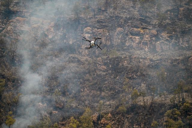 Officials from the East Java Provincial Disaster Management Agency use a drone carrying water to battle a wildfire in the Bromo Tengger Semeru National Park near Mount Bromo in Probolinggo, East Java province on August 6, 2026. (Photo by JUNI KRISWANTO / AFP)
