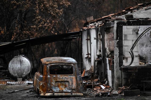 This photograph shows a burnt car parked next to a burnt house in a forest and residential area hit by the wildfire that swept through the Gironde region in Le Porge, south-western France on August 6, 2026. (Photo by Christophe ARCHAMBAULT / AFP)