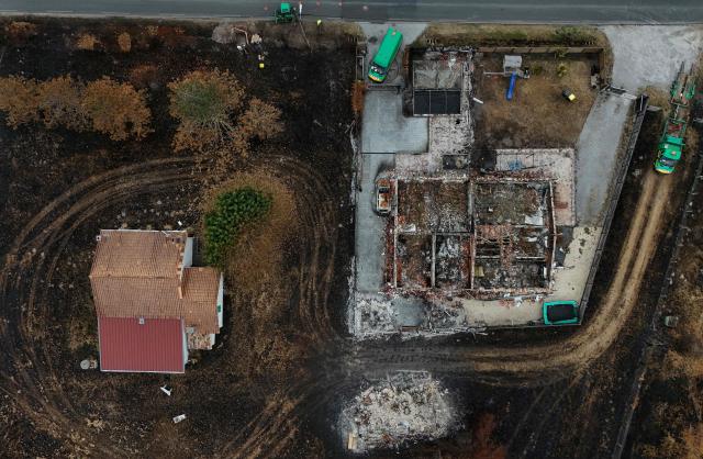 This aerial photograph shows a burnt (R) and an intact property in an area hit by the wildfire that swept through the Gironde region in Le Porge, south-western France on August 6, 2026. Around 240 homes were destroyed by the flames, three-quarters of them in the municipality of Le Porge (population 3,500), according to a provisional assessment. No fatalities or civilian injuries have been reported. (Photo by Christophe ARCHAMBAULT / AFP)