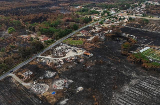 This aerial photograph shows burnt properties (foreground) in an area hit by the wildfire that swept through the Gironde region in Le Porge, south-western France on August 6, 2026. Around 240 homes were destroyed by the flames, three-quarters of them in the municipality of Le Porge (population 3,500), according to a provisional assessment. No fatalities or civilian injuries have been reported. (Photo by Christophe ARCHAMBAULT / AFP)