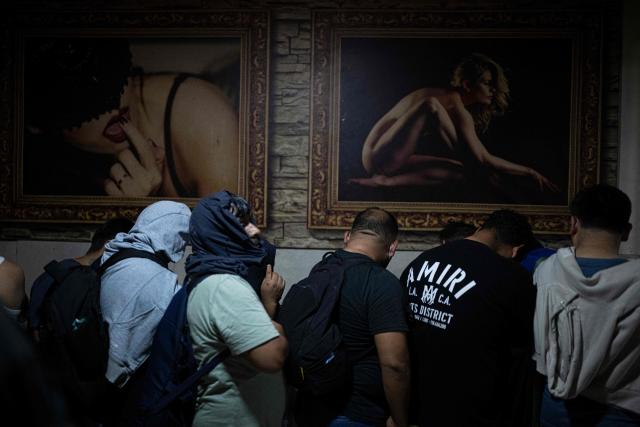 Men wait to undergo an identity check during an anti-human trafficking police operation called Sodom and Gomorrah at La Miel brothel, in the Independencia district, on the northern outskirts of Lima on July 31, 2026 late night. (Photo by ERNESTO BENAVIDES / AFP)