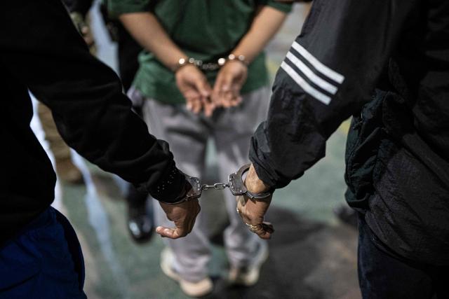 Handcuffed detainees are seen during an anti-human trafficking police operation called Sodom and Gomorrah at La Miel brothel, in the Independencia district, on the northern outskirts of Lima on August 1, 2026. (Photo by ERNESTO BENAVIDES / AFP)