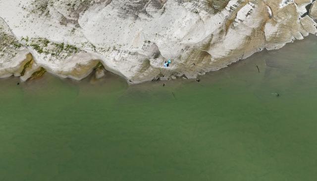 This aerial photograph shows people walking on the sandbanks exposed by the receding waters of the Po River in Isola Pescaroli, northern Italy, on August 6, 2026. (Photo by Stefano RELLANDINI / AFP)