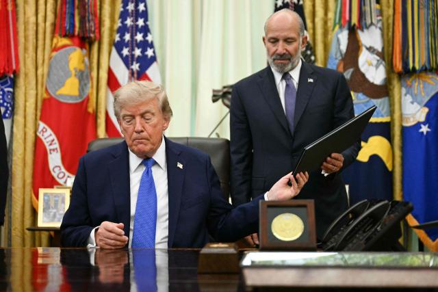 US President Donald Trump passes a newly signed executive order on adjusting imports of polysilicon to US Secretary of Commerce Howard Lutnick in the Oval Office of the White House in Washington, DC, on August 7, 2026. (Photo by Jim WATSON / AFP)