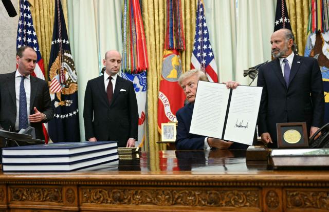 US President Donald Trump holds up a newly signed executive order on adjusting imports of polysilicon in the Oval Office of the White House in Washington, DC, on August 7, 2026. (Photo by Jim WATSON / AFP)