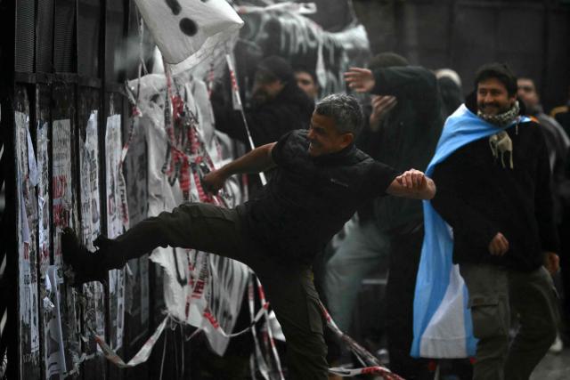 A demonstrator kicks a fence during a protest outside the National Congress in Buenos Aires on August 6, 2026, as senators debate a bill on the inviolability of private property. (Photo by Luis ROBAYO / AFP)