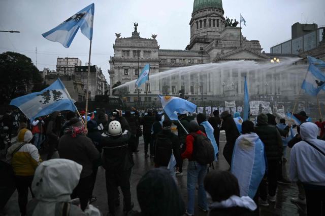 Riot police fire a water cannon to disperse demonstrators protesting outside the National Congress in Buenos Aires on August 6, 2026, as senators debate a bill on the inviolability of private property. (Photo by Luis ROBAYO / AFP)