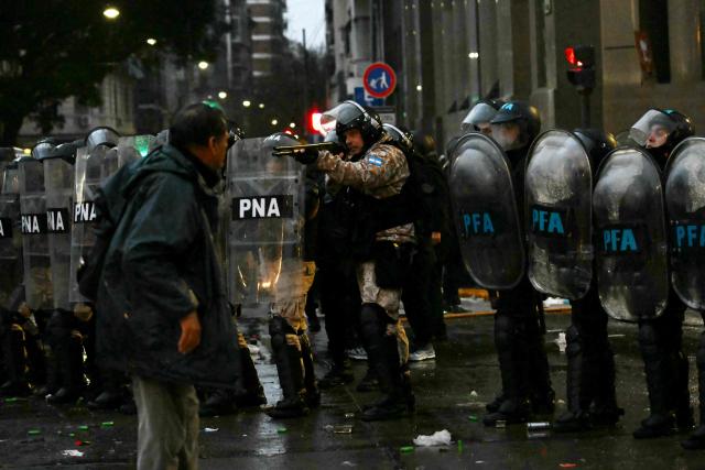 A riot police aims a shotgun during a protest outside the National Congress in Buenos Aires on August 6, 2026, as senators debate a bill on the inviolability of private property. (Photo by Luis ROBAYO / AFP)