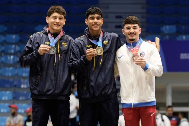 Colombia's Angel Barajas (C), Colombia's Yan Dairo Zabala (L) and Puerto Rico's Francisco Velez pose on the podium after winning the gold, silver and bronze medals, respectively, in the men's parallel bars final during the XXV Central American and Caribbean Games in Santo Domingo on August 6, 2026. (Photo by Francesco SPOTORNO / AFP)