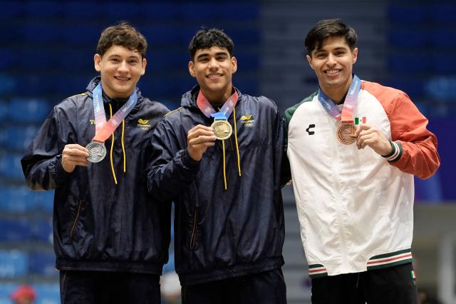 Colombia's Angel Barajas (C), Colombia's Yan Dairo Zabala (L) and Mexico's Isaac Nunez pose on the podium after winning the gold, silver and bronze medals, respectively, in the men's horizontal bar final during the XXV Central American and Caribbean Games in Santo Domingo on August 6, 2026. (Photo by Francesco SPOTORNO / AFP)