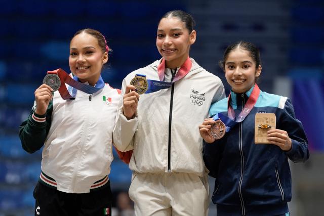 Panama's Alyiah Lide (C), Mexico's Natalia Escalera (L) and Guatemala's Brithany Herrera pose on the podium after winning the gold, silver and bronze medals, respectively, in the women's balance beam final during the XXV Central American and Caribbean Games in Santo Domingo on August 6, 2026. (Photo by Francesco SPOTORNO / AFP)