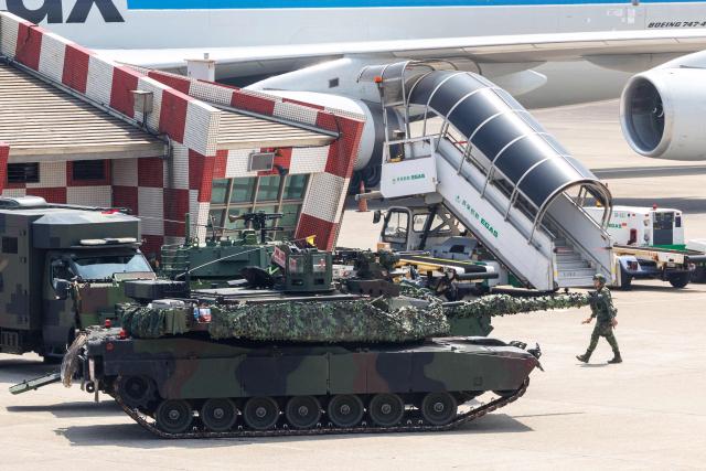 A Taiwanese military M1A2T tank is pictured next to aircraft during a drill simulating an enemy airborne assault at Taiwan Taoyuan International Airport in Taoyuan on August 7, 2026. Taiwan's largest military drills of the year began on August 5 as the island democracy attempts to prepare its population for a potential Chinese invasion. (Photo by CHENG Yu-chen / AFP)