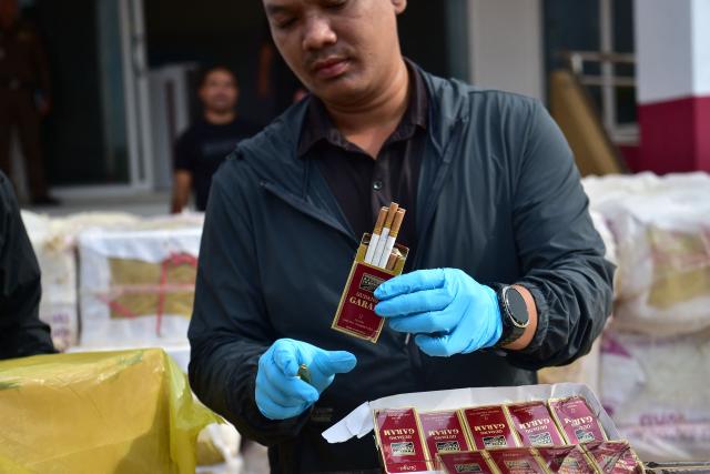A Thai official holds confiscated cigarette cartons following an operation to seize the smuggled items worth over 20 million THB (600,000 USD) at the Narathiwat Provincial Police Station in the southern Thai province of Narathiwat on August 7, 2026. (Photo by Madaree TOHLALA / AFP)