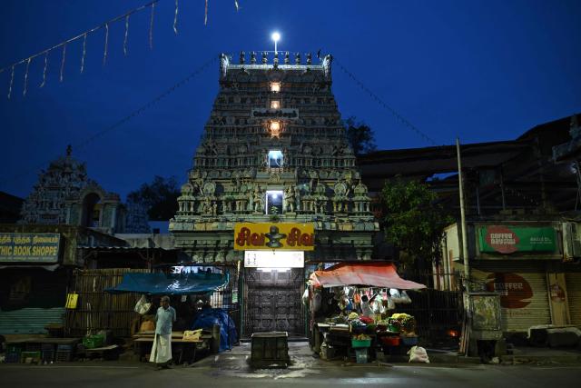 A shopkeeper opens his stall in front of a temple, at dawn in Chennai on August 7, 2026. (Photo by R.Satish BABU / AFP)
