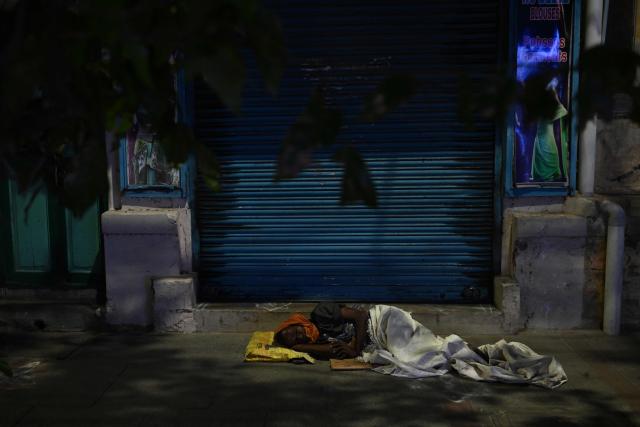 A man sleeps outside a closed shop, at dawn in Chennai on August 7, 2026. (Photo by R.Satish BABU / AFP)