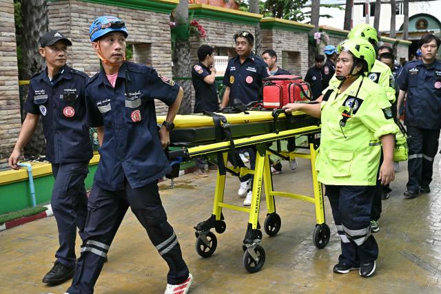 Emergency responders walk with a stretcher outside a school following a shooting in Bang Kruai district, Nonthaburi province, north of Thailand's capital Bangkok, on August 7, 2026. At least two people were killed and several others wounded in a school shooting north of the Thai capital Bangkok on August 7, a Nonthaburi provincial official told AFP. (Photo by Lillian SUWANRUMPHA / AFP)