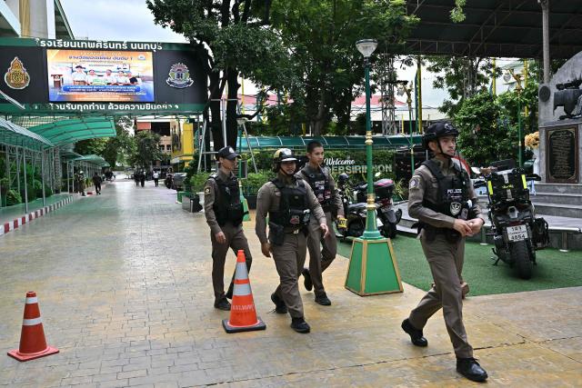 Police walk at a school premises following a shooting in Bang Kruai district, Nonthaburi province, north of Thailand's capital Bangkok, on August 7, 2026. At least two people were killed and several others wounded in a school shooting north of the Thai capital Bangkok on August 7, a Nonthaburi provincial official told AFP. (Photo by Lillian SUWANRUMPHA / AFP)