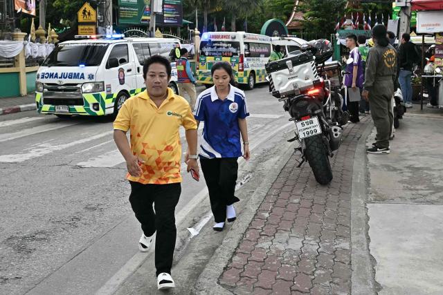 A student walks past ambulances lined up outside a school following a shooting in Bang Kruai district, Nonthaburi province, north of Thailand's capital Bangkok, on August 7, 2026. Two people were killed and 15 wounded in a school shooting in a province just north of the Thai capital Bangkok on August 7, local media reported. (Photo by Lillian SUWANRUMPHA / AFP)