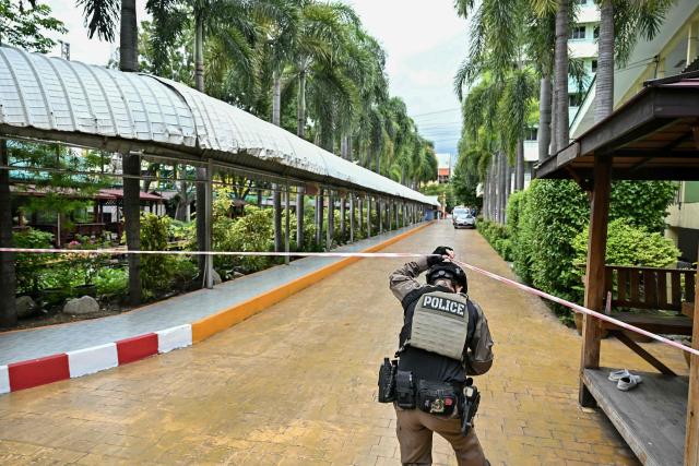 A policeman holds up a cordon tape after a school shooting in Bang Kruai district, Nonthaburi province, north of Thailand's capital Bangkok, on August 7, 2026. At least two people were killed and several others wounded in a school shooting north of the Thai capital Bangkok on August 7, a Nonthaburi provincial official told AFP. (Photo by Lillian SUWANRUMPHA / AFP)