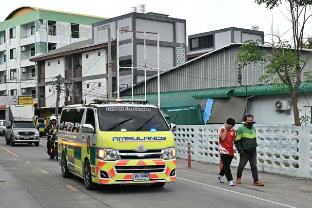 A student leaves with a parent (R) as an ambulance drives past after a school shooting in Bang Kruai district, Nonthaburi province, north of Thailand's capital Bangkok, on August 7, 2026. At least four people were killed and 15 students injured during a school shooting just north of the Thai capital Bangkok on August 7, the deputy interior minister said. (Photo by Lillian SUWANRUMPHA / AFP)