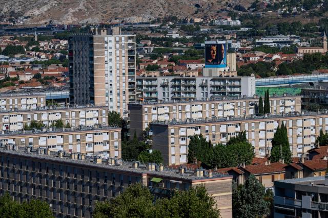 This photo shows an overview of the La Castellane neighborhood in northern Marseille, southern France, with two large-format portraits of newly appointed France head coach Zinedine Zidane, one from his youth and one recent, displayed on the facade of a building in the background, on August 7, 2026. (Photo by Miguel MEDINA / AFP)
