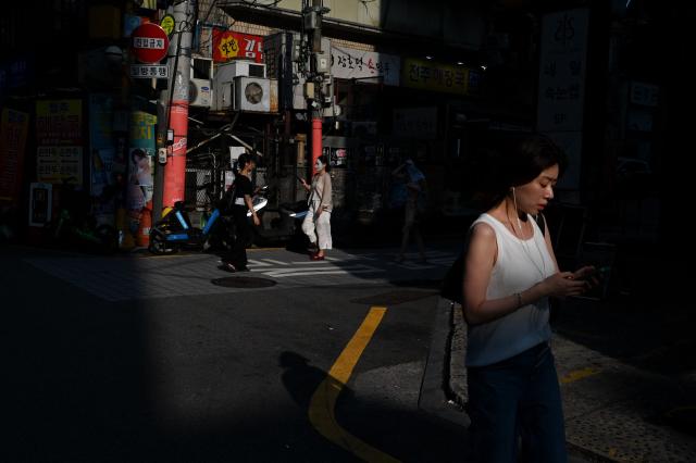 People walk on a street on a hot day in Seoul on August 7, 2026. South Korea has been sweltering in a streak of searing weather -- new all-time highs were set three times over the past week alone, peaking at 42.5C on August 2. (Photo by Greg Baker / AFP)