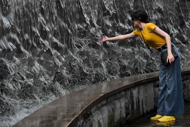 A woman touches water in a fountain in Manezhnaya Square on a hot day in central Moscow on August 7, 2026. (Photo by Igor IVANKO / AFP)